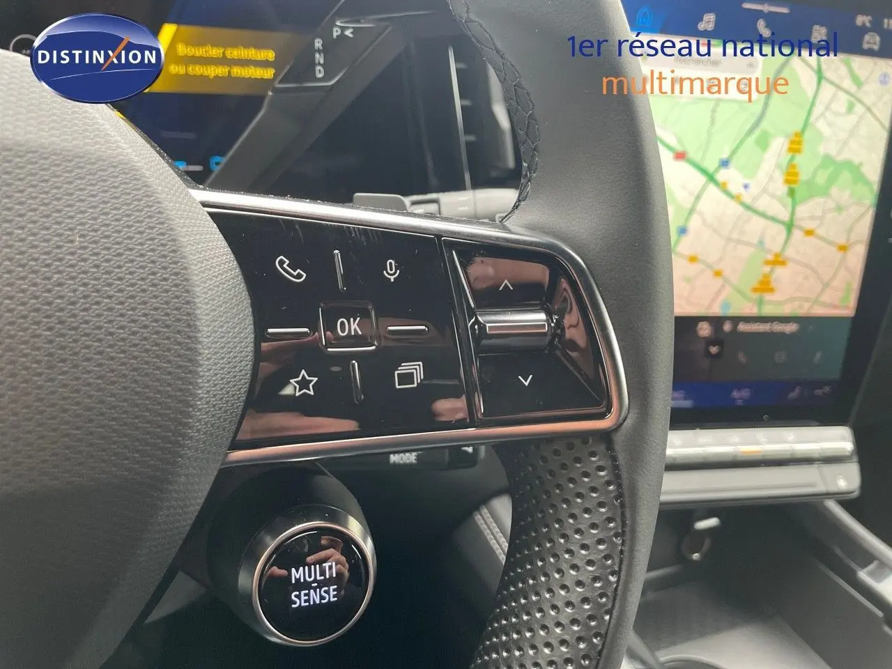 Gros plan sur le volant perforé et les commandes tactiles du Renault Austral gris schiste avec écran GPS en arrière-plan.