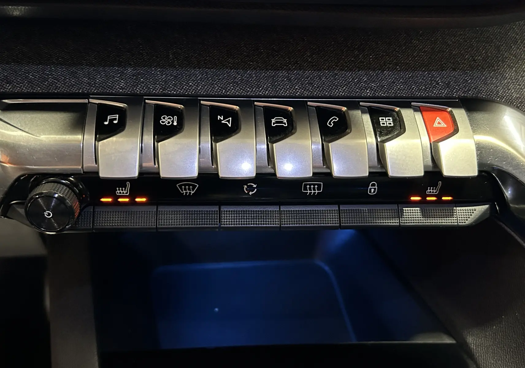 Gros plan sur la rangée de boutons argentés du tableau de bord du Peugeot 5008 gris, avec sièges chauffants activés.