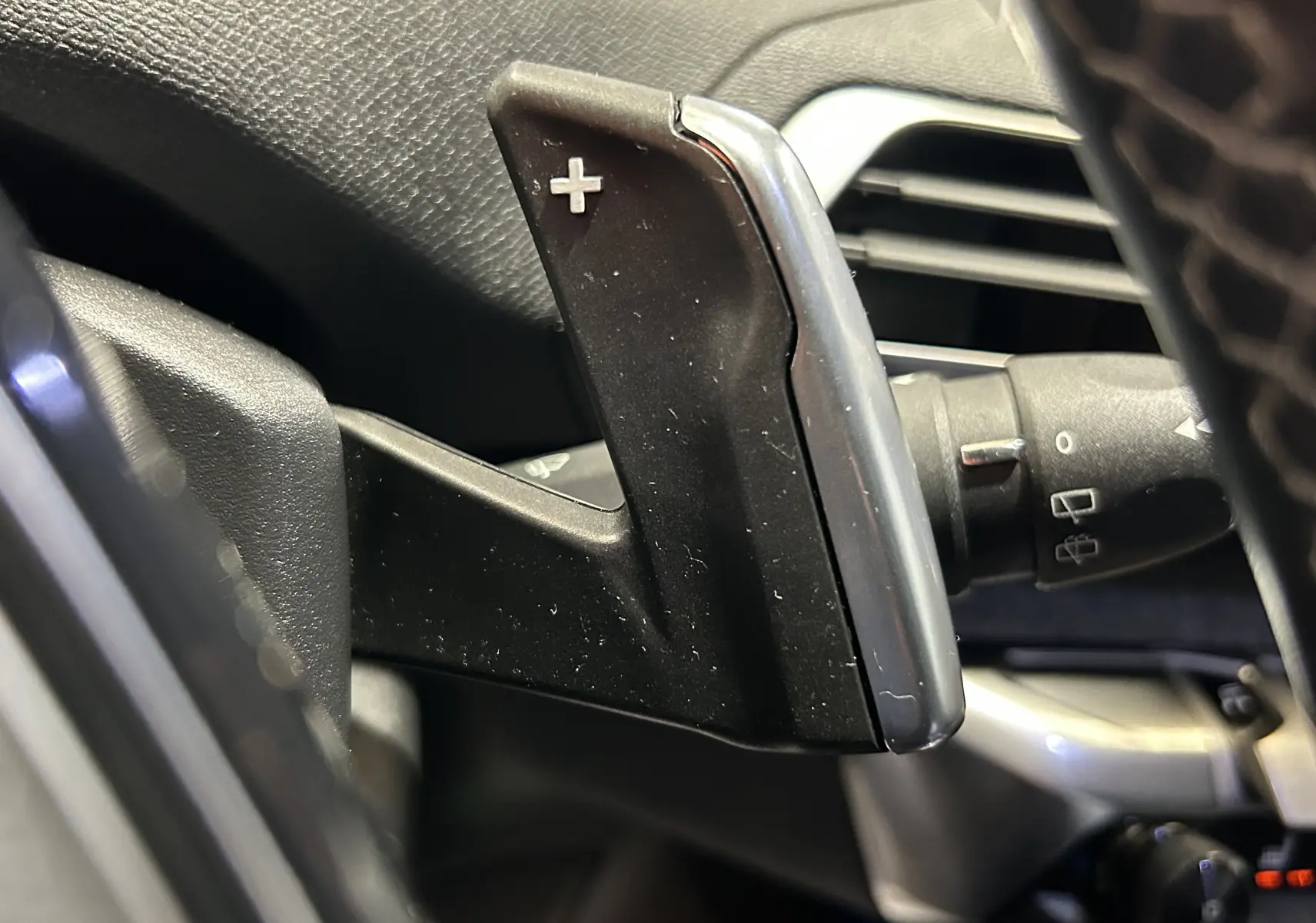Gros plan sur la palette de changement de vitesse "+" côté droit du volant dans l'habitacle du Peugeot 5008 gris 2020.