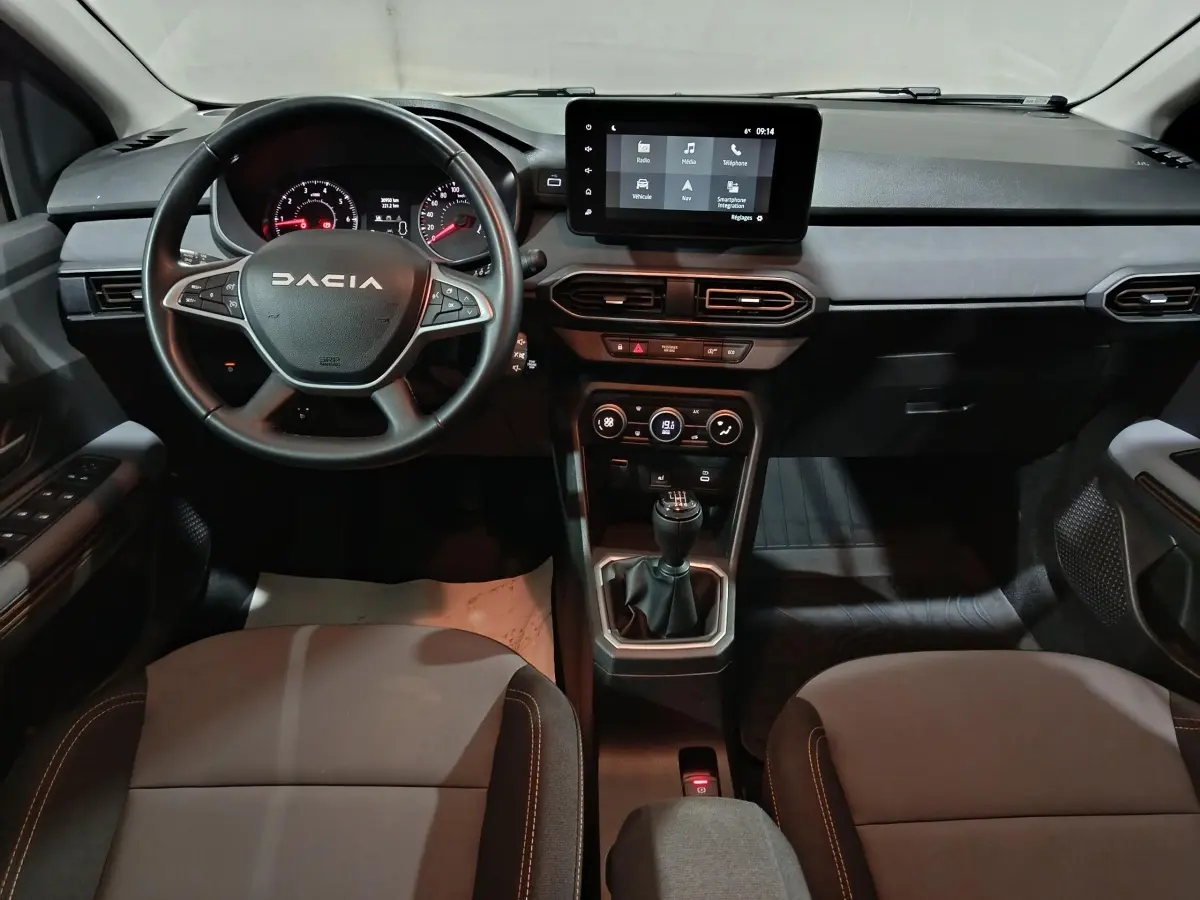 Vue intérieure avant du tableau de bord de la Dacia Sandero Extreme+ 2024 avec volant cuir multifonctions et écran tactile central.