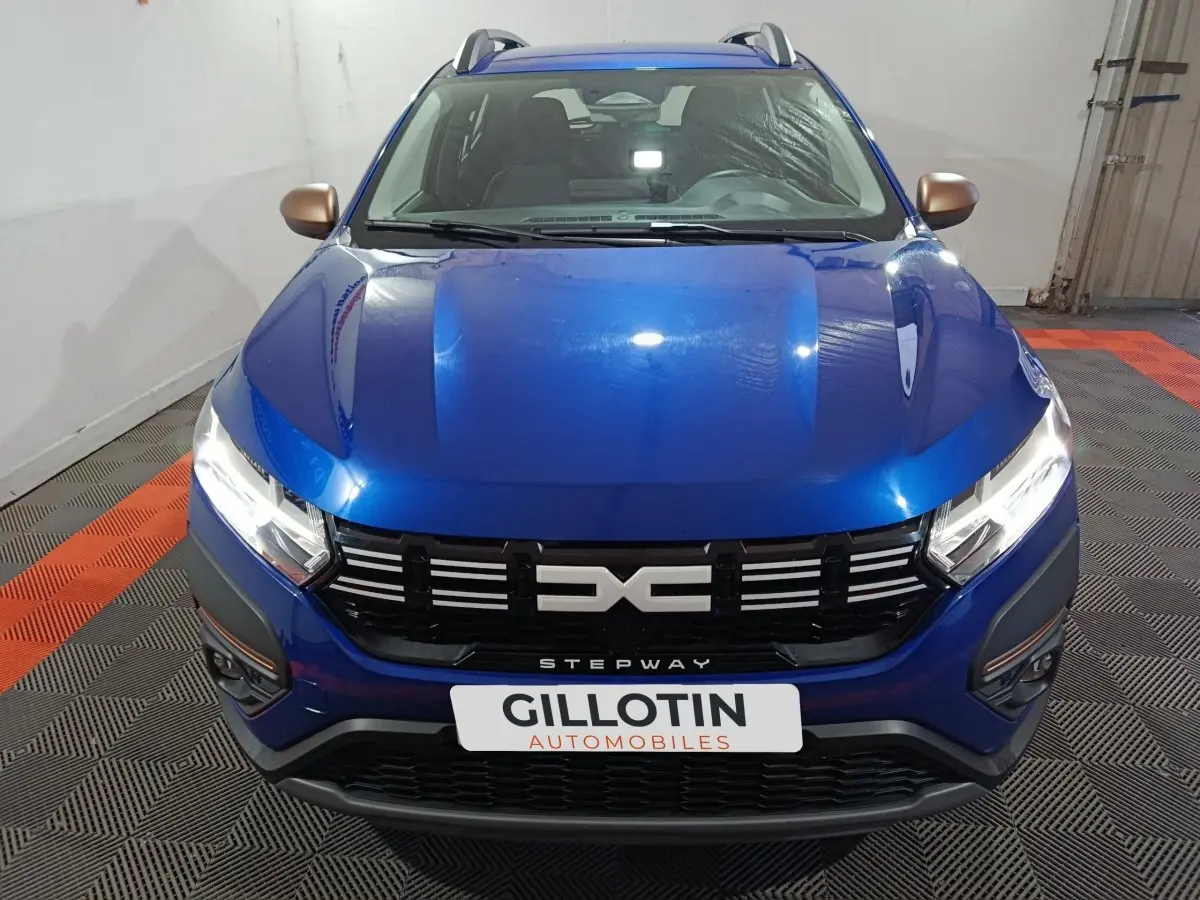 Vue avant rapprochée d'une Dacia Sandero Extreme+ TCe 110 2024 bleu avec calandre noire et rétroviseurs bronze.