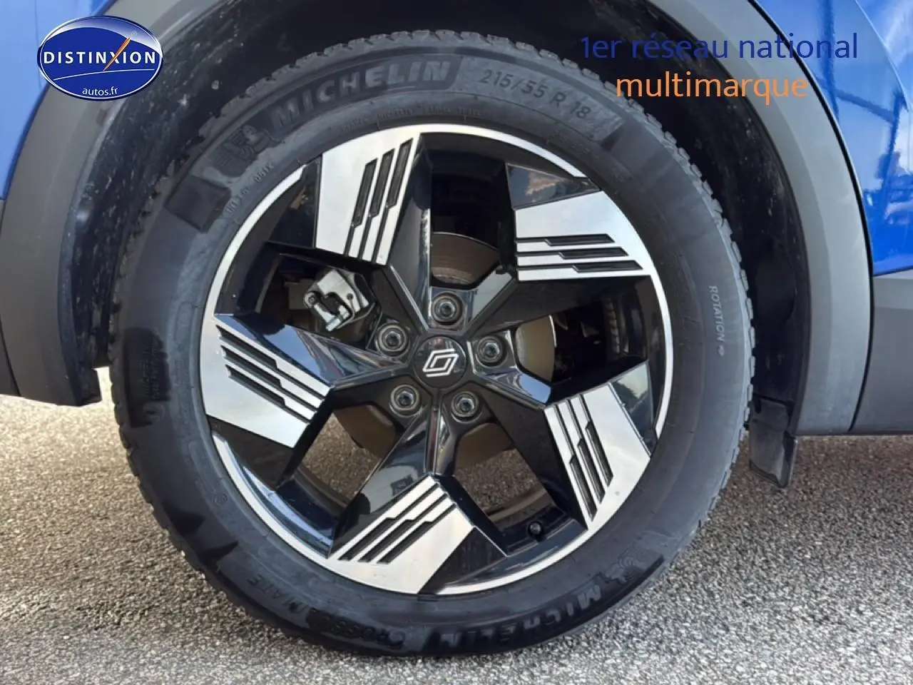 Gros plan sur la roue avant droite du Renault Symbioz bleu iron metal, jante alliage noire et argentée au design géométrique.