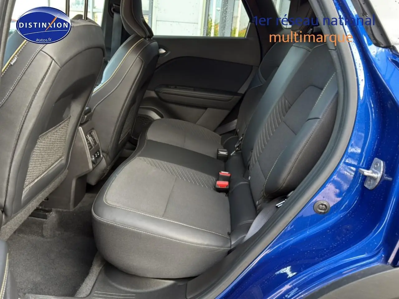 Vue côté droit sur l'intérieur arrière du Renault Symbioz bleu iron metal, sièges tissu et cuir noir avec surpiqûres claires.