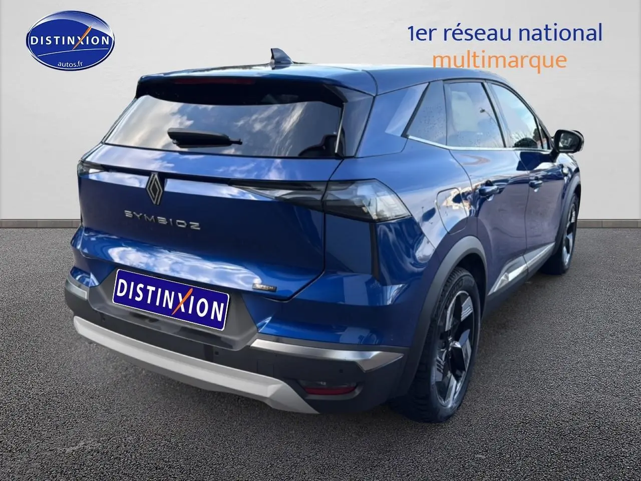 Vue 3/4 arrière droite du Renault Symbioz bleu iron metal avec vitres surteintées et barres de toit visibles.