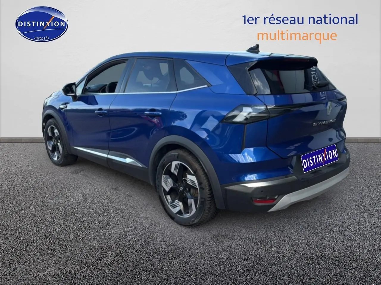 Vue 3/4 arrière gauche d’un Renault Symbioz bleu iron metal avec vitres arrière surteintées et jantes distinctives.