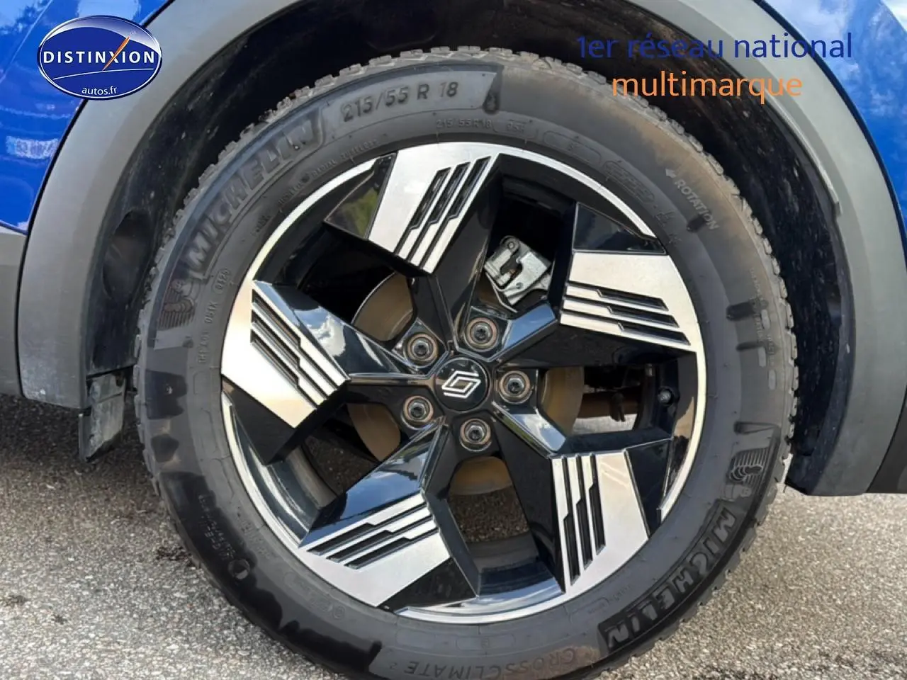 Gros plan sur la roue avant droite d'une Renault Symbioz bleu iron metal avec jante noire et argentée design moderne.