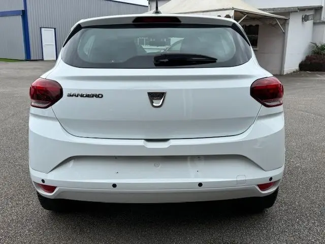 Vue arrière d'une Dacia Sandero 2023 blanc glacier, avec feux rouges et logo central bien visibles.