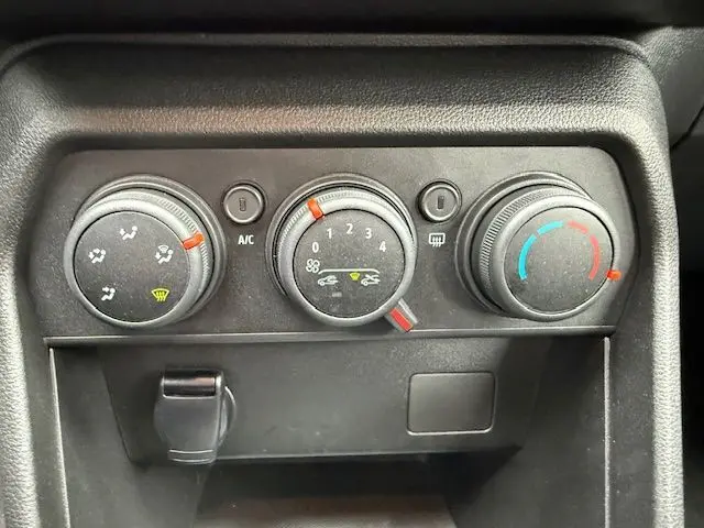 Gros plan sur les commandes manuelles de climatisation du tableau de bord d'une Dacia Sandero blanche Glacier 2023.