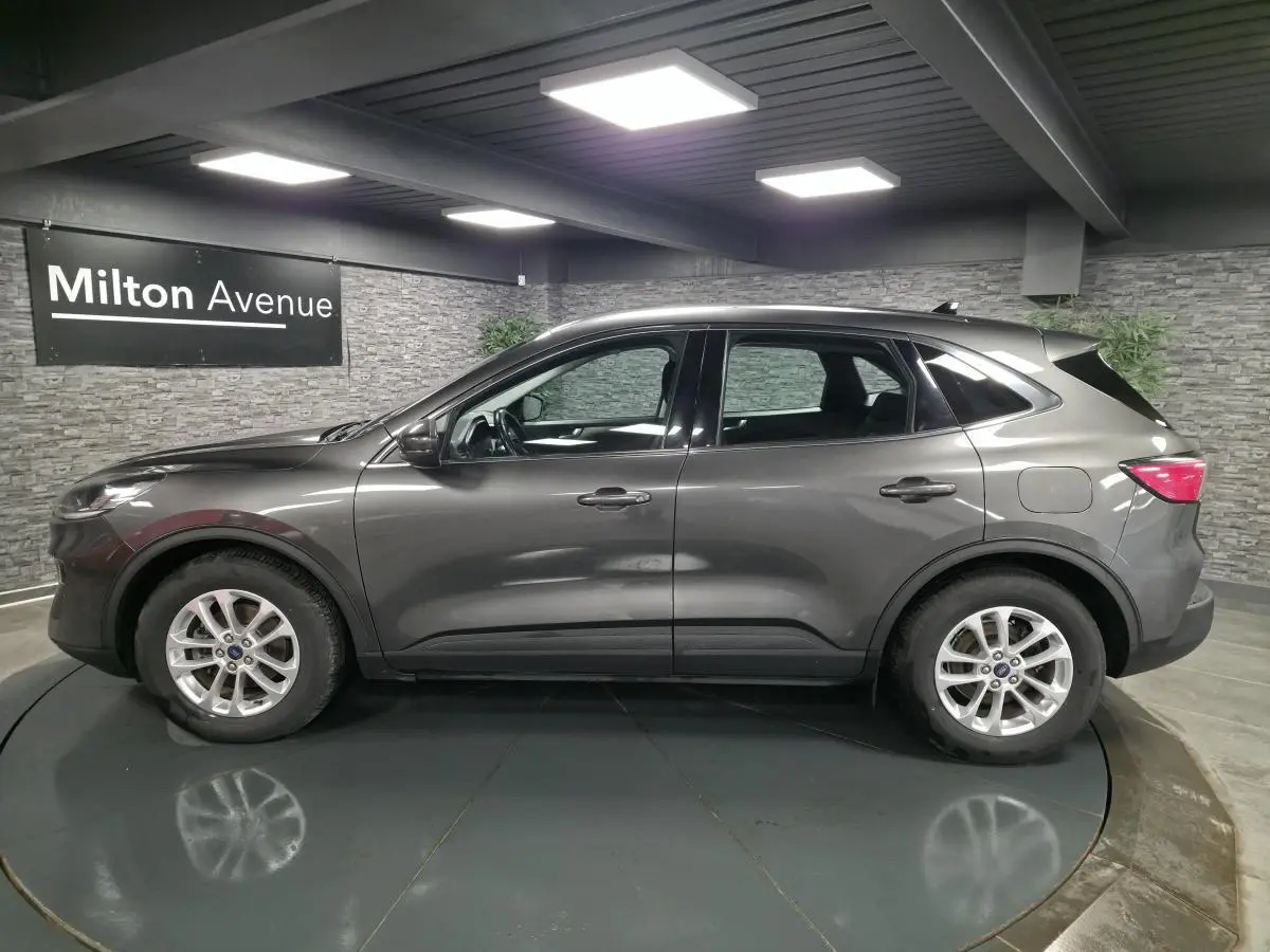 Ford Kuga gris métallisé vue de profil côté gauche dans un showroom avec jantes alliage 17 pouces.