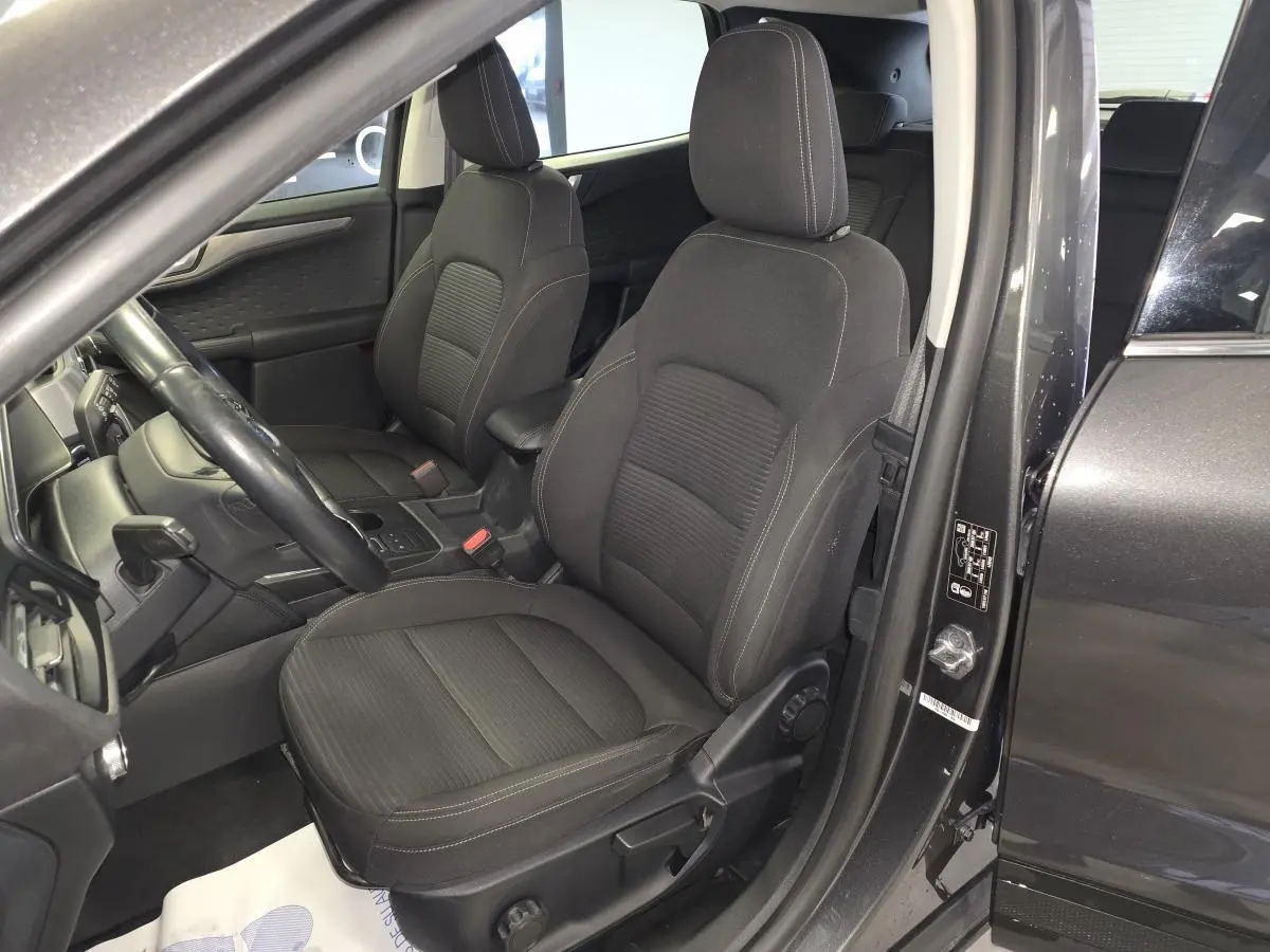 Vue intérieure côté conducteur du Ford Kuga gris 2020, sièges tissu noir avec coutures contrastées.