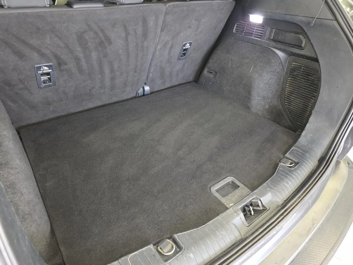 Coffre spacieux et propre du Ford Kuga gris, vue intérieure arrière avec éclairage et fixations Isofix visibles.
