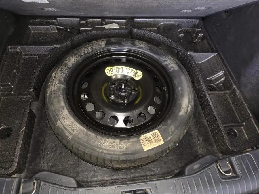 Gros plan sur la roue de secours galette noire 17 pouces dans le coffre du Ford Kuga gris 2020.