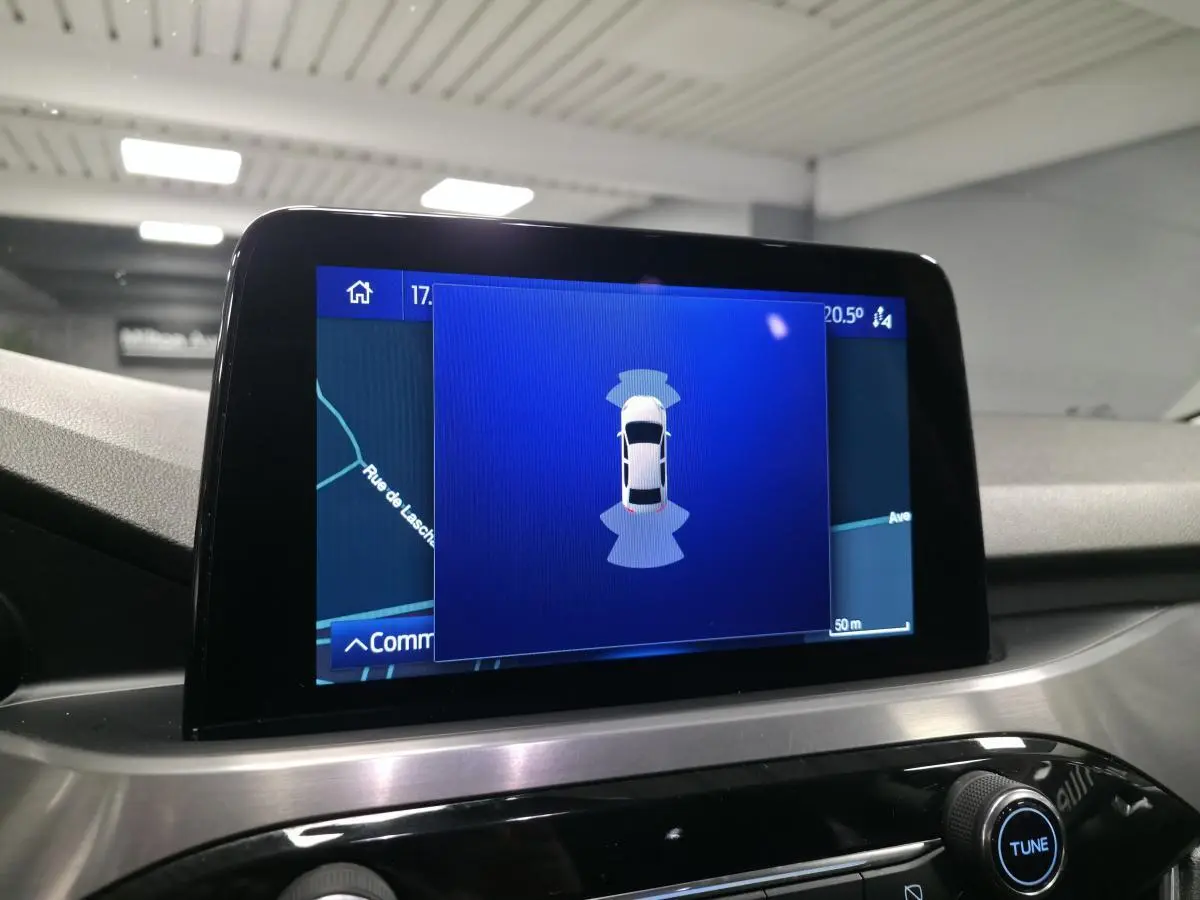 Écran tactile central du Ford Kuga gris 2020 affichant l'aide au stationnement avec vue du véhicule en plan dessus.