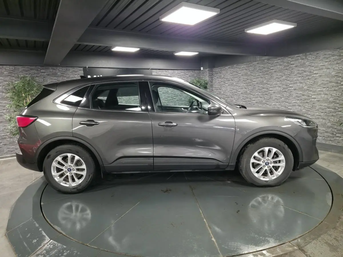 Vue latérale droite d'un Ford Kuga gris métallisé 2020 avec jantes alliage 17 pouces en intérieur showroom.