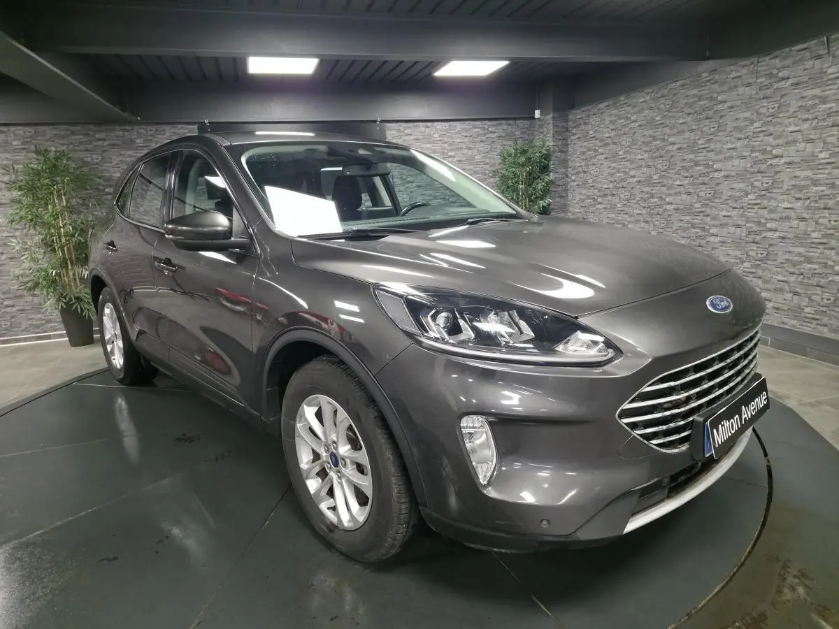 Ford Kuga gris métallisé en 3/4 avant droit avec calandre chromée et jantes alliage 17 pouces dans un showroom.