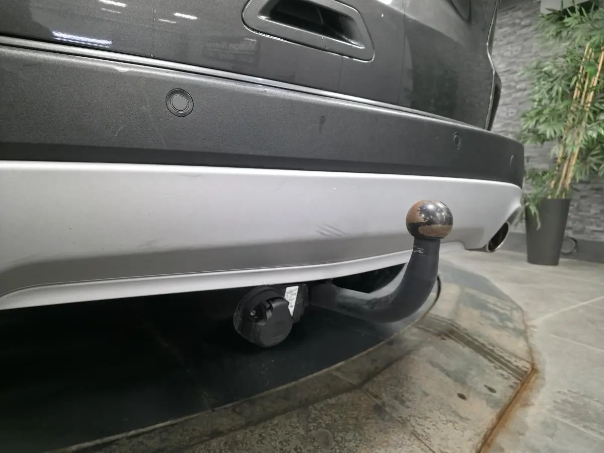 Gros plan sur l'attelage fixe arrière d'un Ford Kuga gris 2020, avec prise électrique visible sous le pare-chocs.