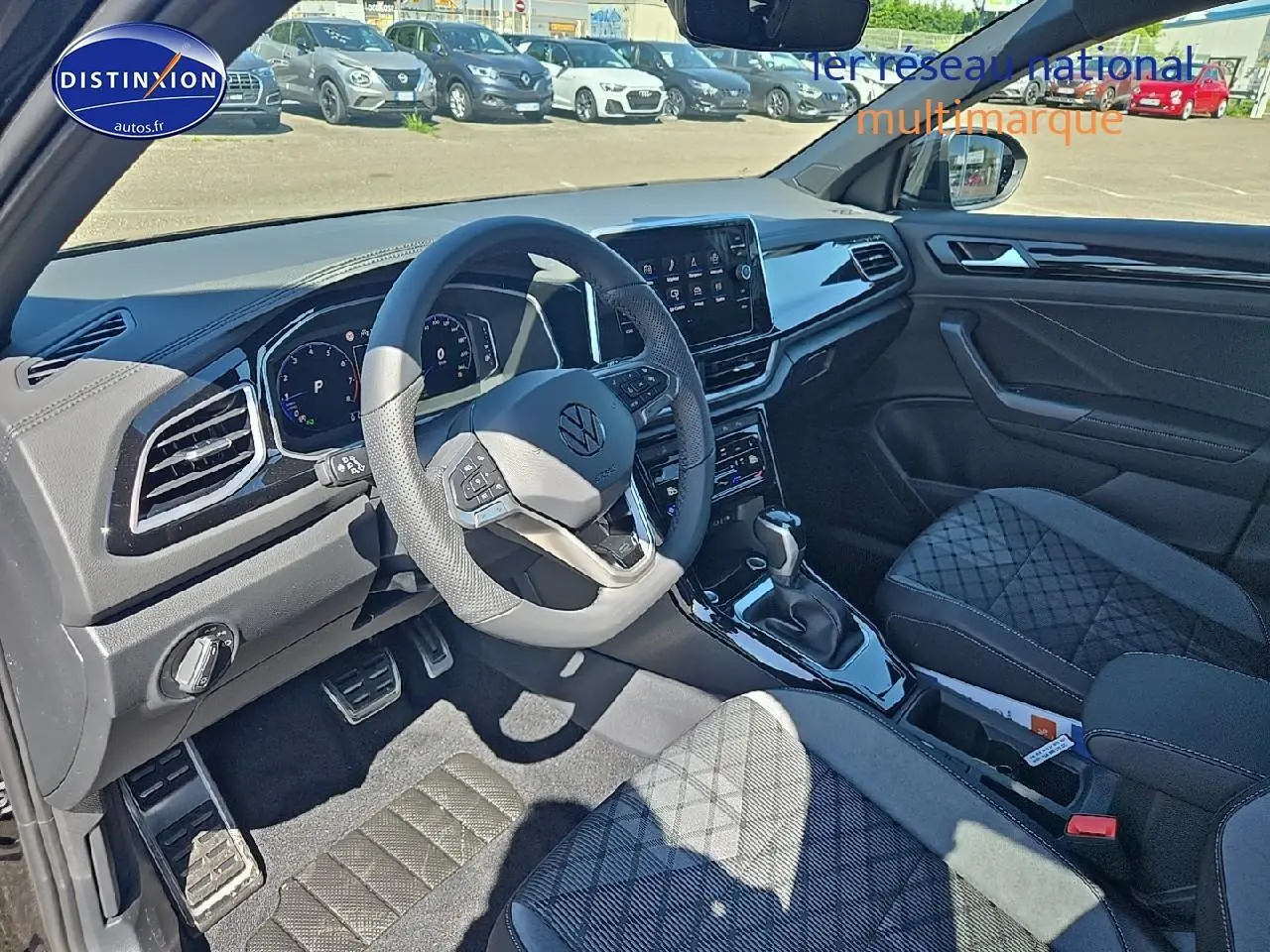 Intérieur avant du Volkswagen T-Roc noir perle, volant cuir multifonction et sièges tissu R-Line avec surpiqûres croisées.