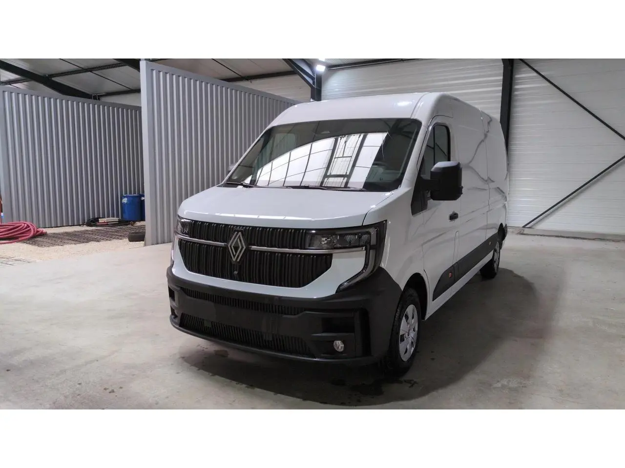 Renault Master blanc vu en 3/4 avant droit dans un garage, avec calandre noire et pare-chocs contrasté.