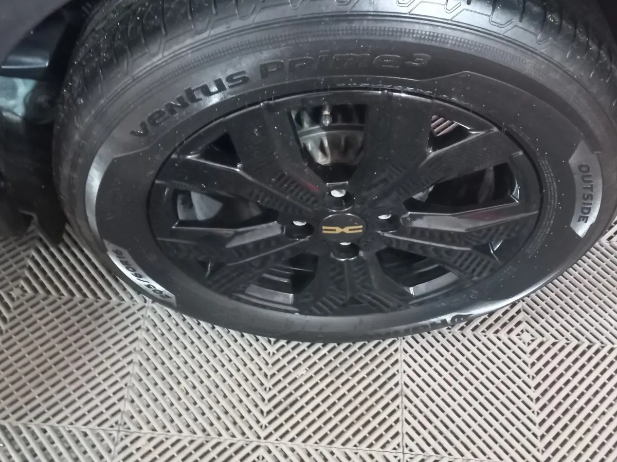 Gros plan sur la roue noire avec jante en alliage du côté gauche de la Dacia Sandero Extreme+ TCe 110 verte.