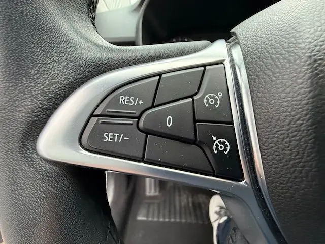 Gros plan sur les commandes de régulateur de vitesse au volant d’une Dacia Sandero blanc glacier 2023.
