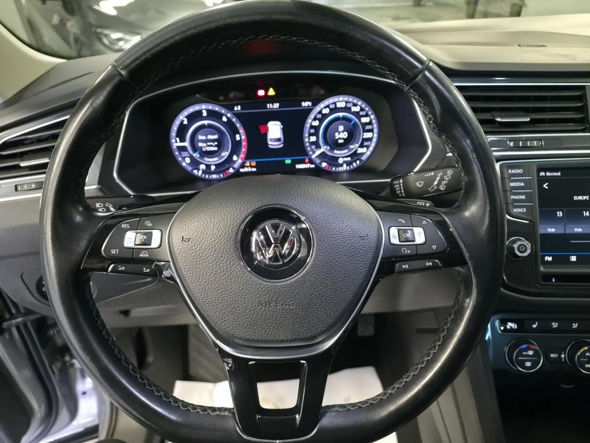 Vue intérieure centrée sur le volant cuir noir multifonctions et le combiné d'instruments digital du Volkswagen Tiguan gris 2016.