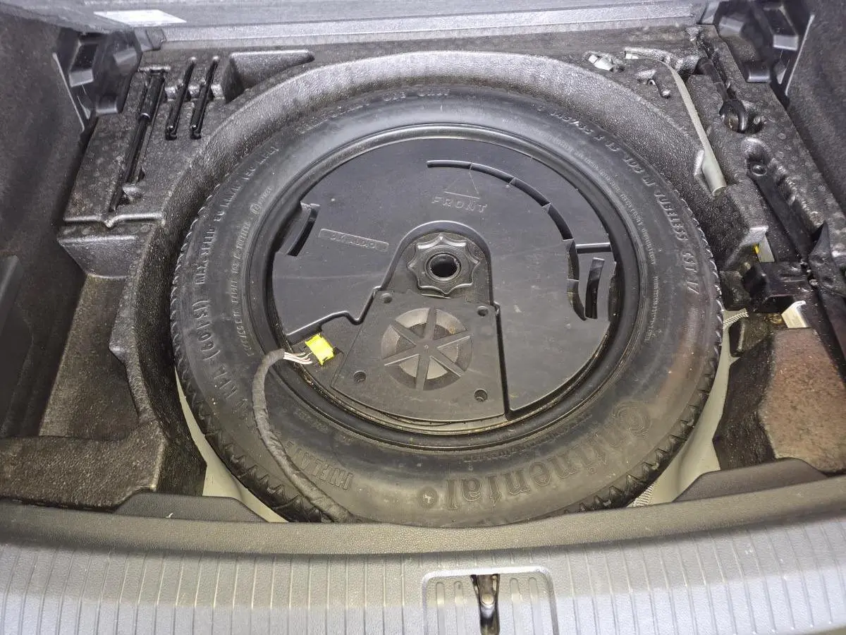 Vue plongeante sur la roue de secours et l'outillage dans le coffre du Volkswagen Tiguan gris 2016.