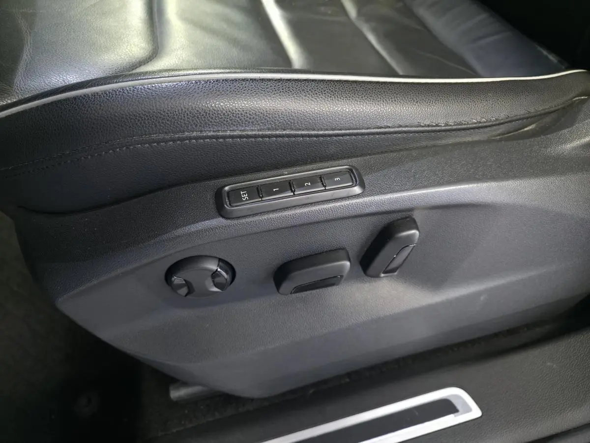Détail des commandes électriques de réglage du siège conducteur en cuir noir du Volkswagen Tiguan gris 2016.