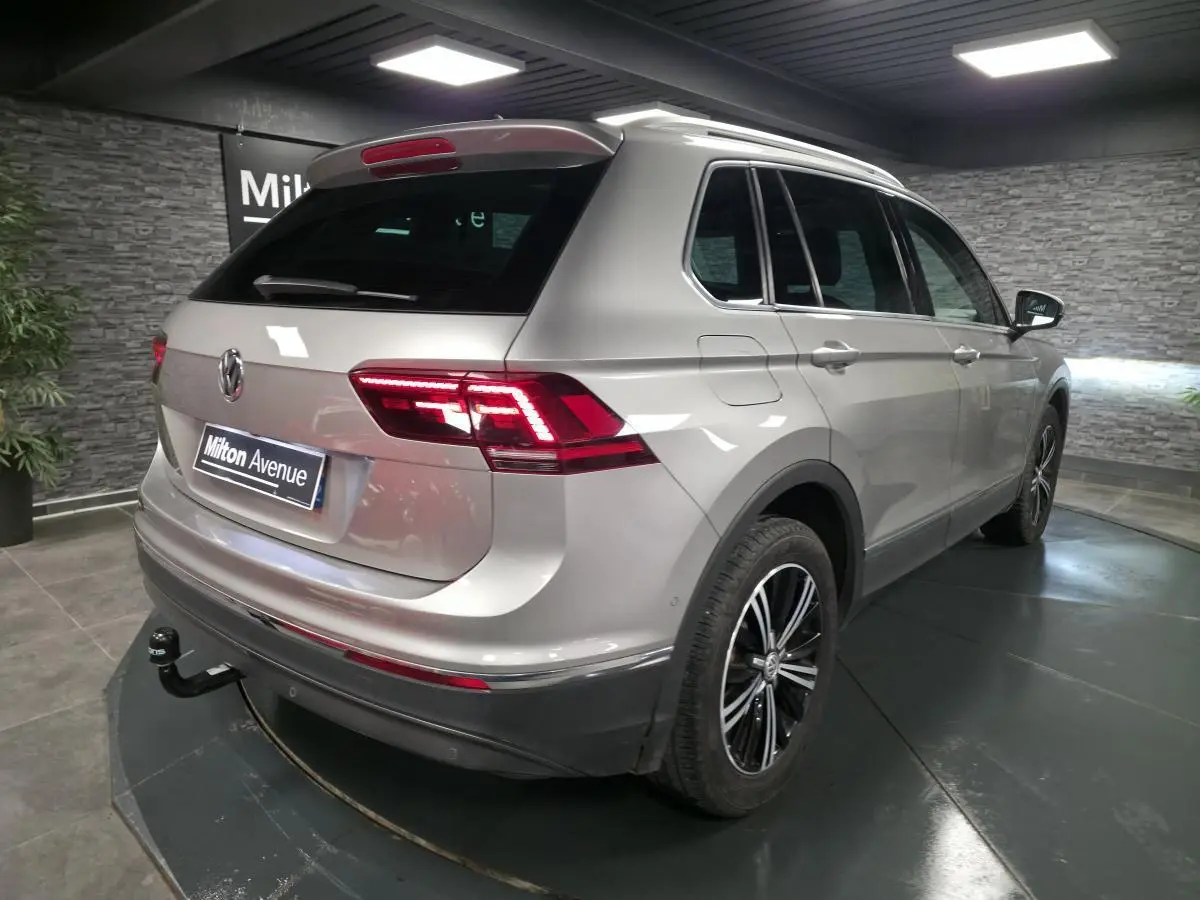 Vue 3/4 arrière droite d'un Volkswagen Tiguan gris avec jantes alliage noires et crochet d'attelage démontable.