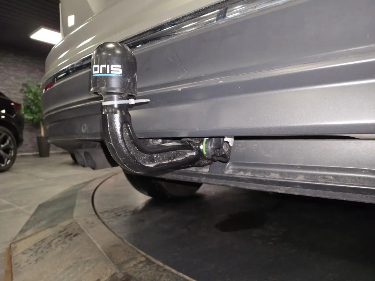 Gros plan sur le crochet d'attelage démontable à l'arrière d'un Volkswagen Tiguan gris 2016 en intérieur.