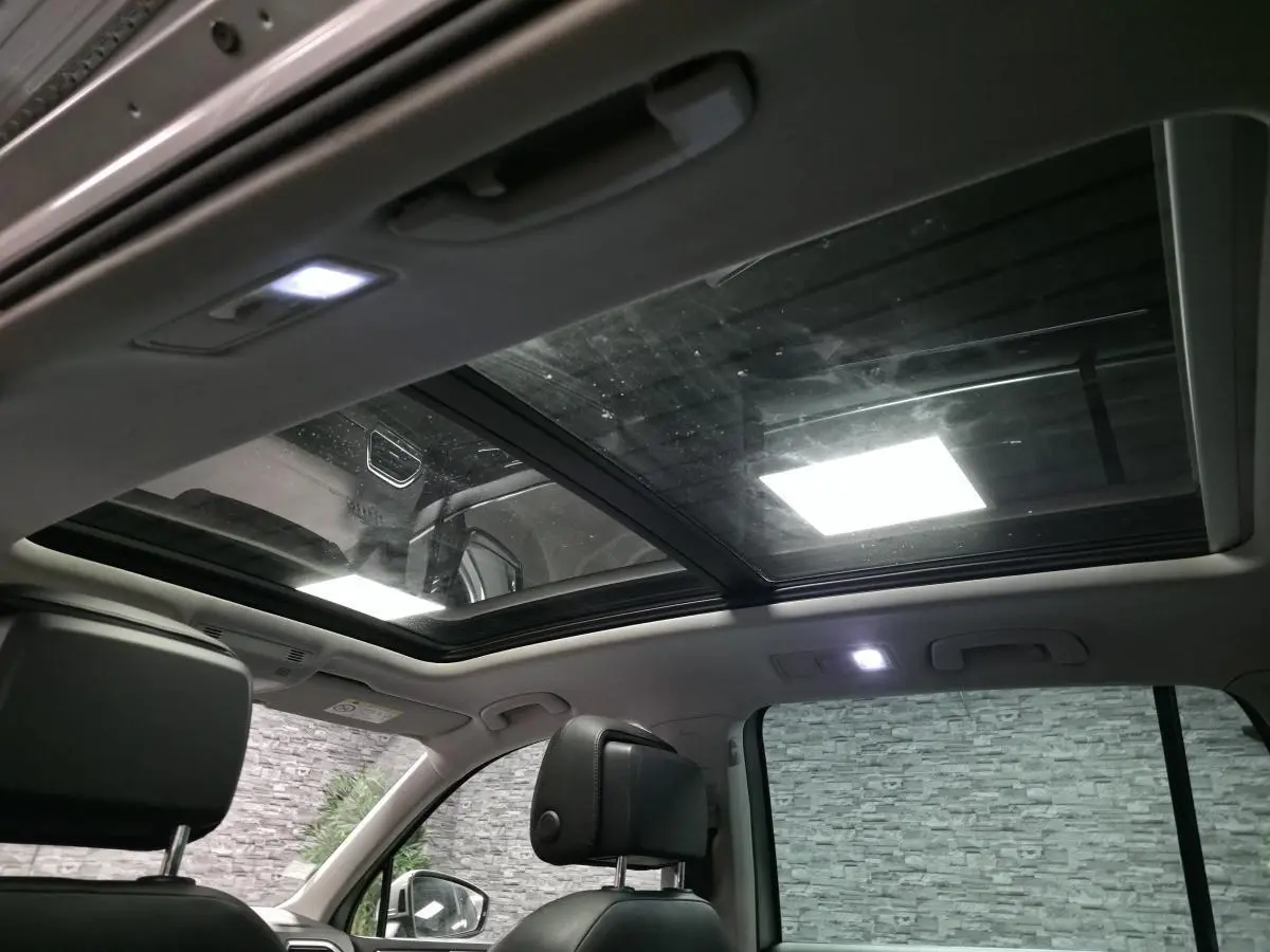 Vue intérieure du toit ouvrant panoramique et des sièges avant en cuir noir du Volkswagen Tiguan gris 2016.