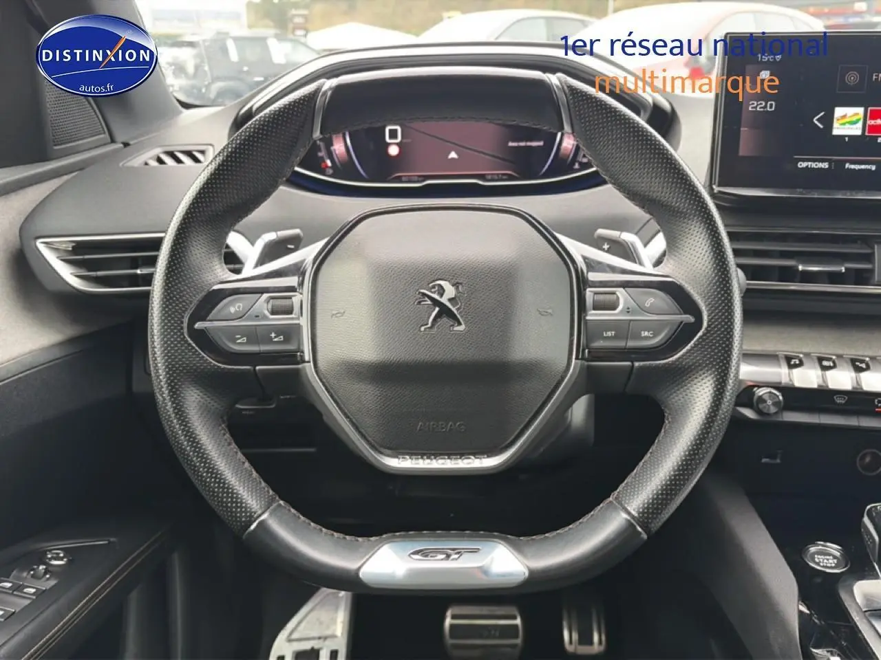Vue rapprochée du volant cuir perforé Peugeot 3008 GT avec commandes multifonctions et logo GT au bas.