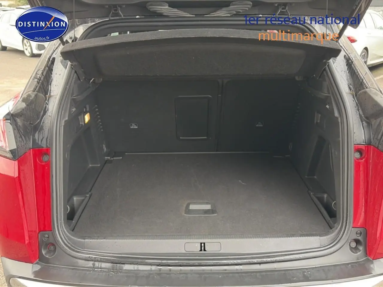 Coffre ouvert vu de l'arrière d'un Peugeot 3008 rouge, montrant l'espace de chargement vide et les finitions intérieures noires.