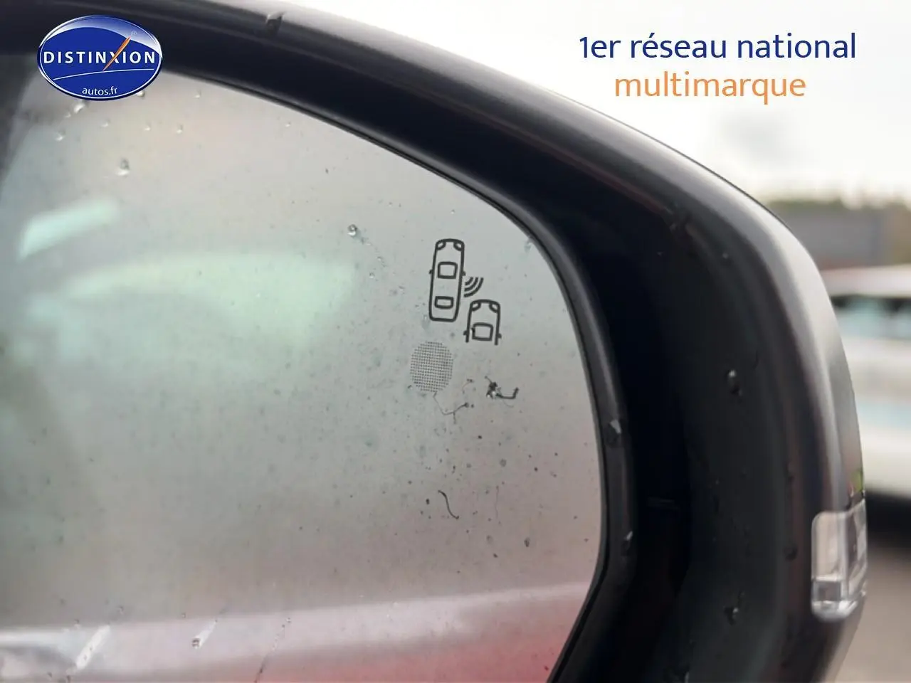 Gros plan sur le rétroviseur extérieur droit noir du Peugeot 3008 rouge, avec icône d'alerte angle mort visible.