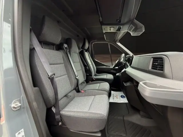 Vue intérieure côté droit du Renault Master 2025 gris foncé, montrant les sièges avant en tissu gris et le tableau de bord.