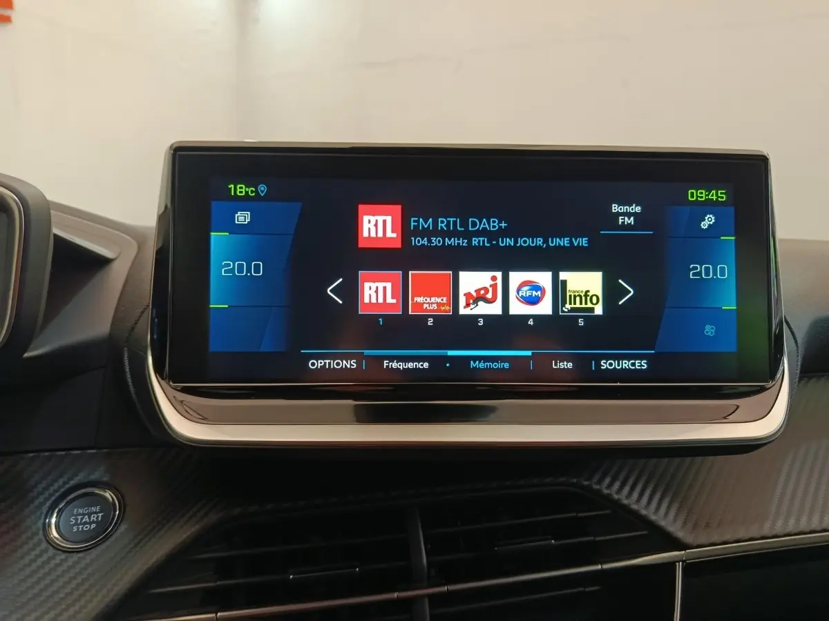 Écran tactile central de 10 pouces affichant la radio dans l'habitacle d'une Peugeot 208 électrique gris clair.