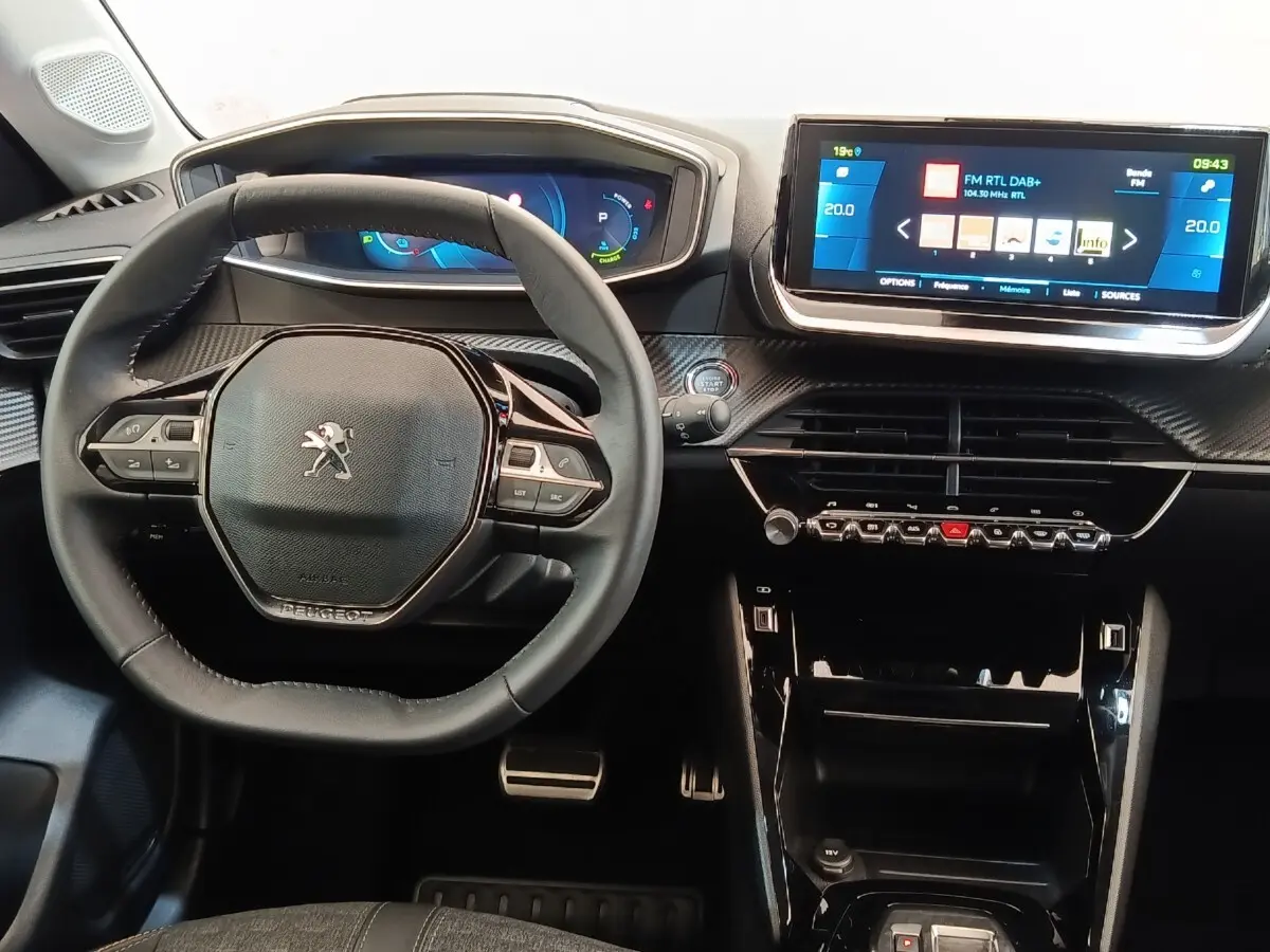 Vue intérieure centrée sur le volant cuir et le tableau de bord avec écran tactile de la Peugeot 208 électrique gris clair.