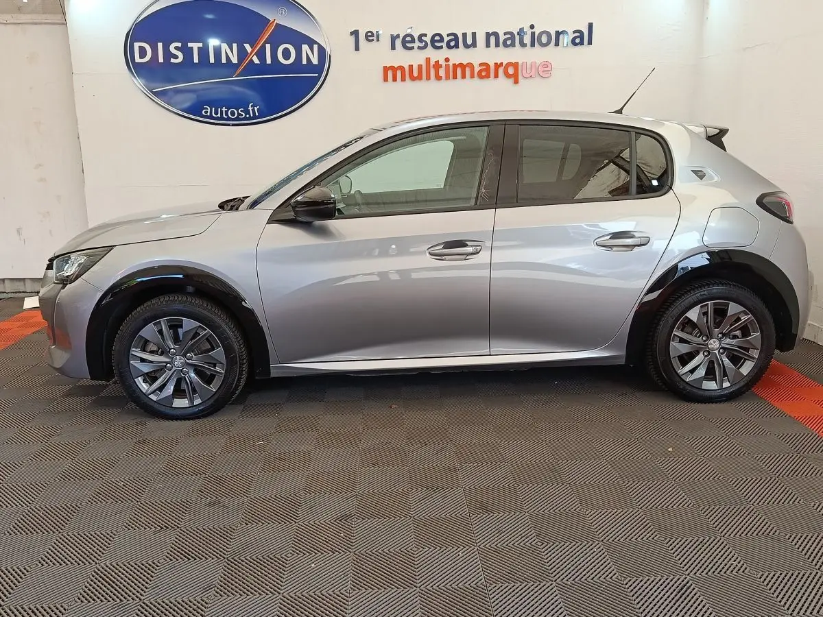 Profil droit d'une Peugeot 208 Electrique Roadtrip gris clair, avec jantes alliage et protections noires sur les passages de roues.