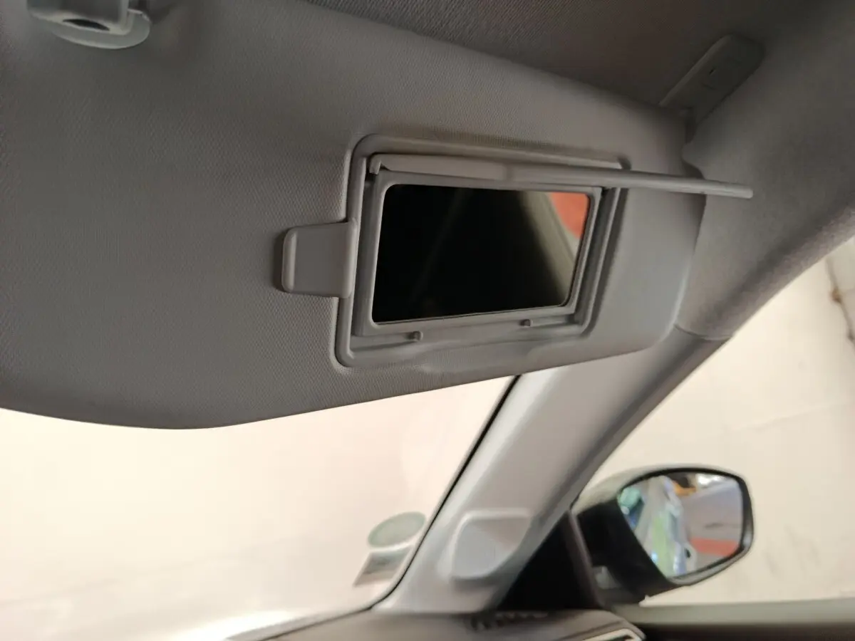 Détail du miroir de courtoisie sur pare-soleil côté conducteur dans l'habitacle gris clair d'une Peugeot 208 Electrique.