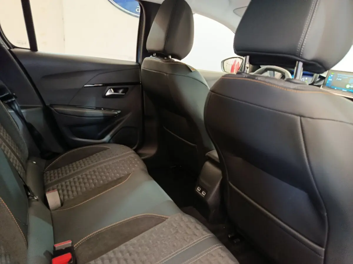 Vue intérieure arrière de la Peugeot 208 Electrique Roadtrip 2022, sièges noirs avec surpiqûres orange et ports USB au centre.