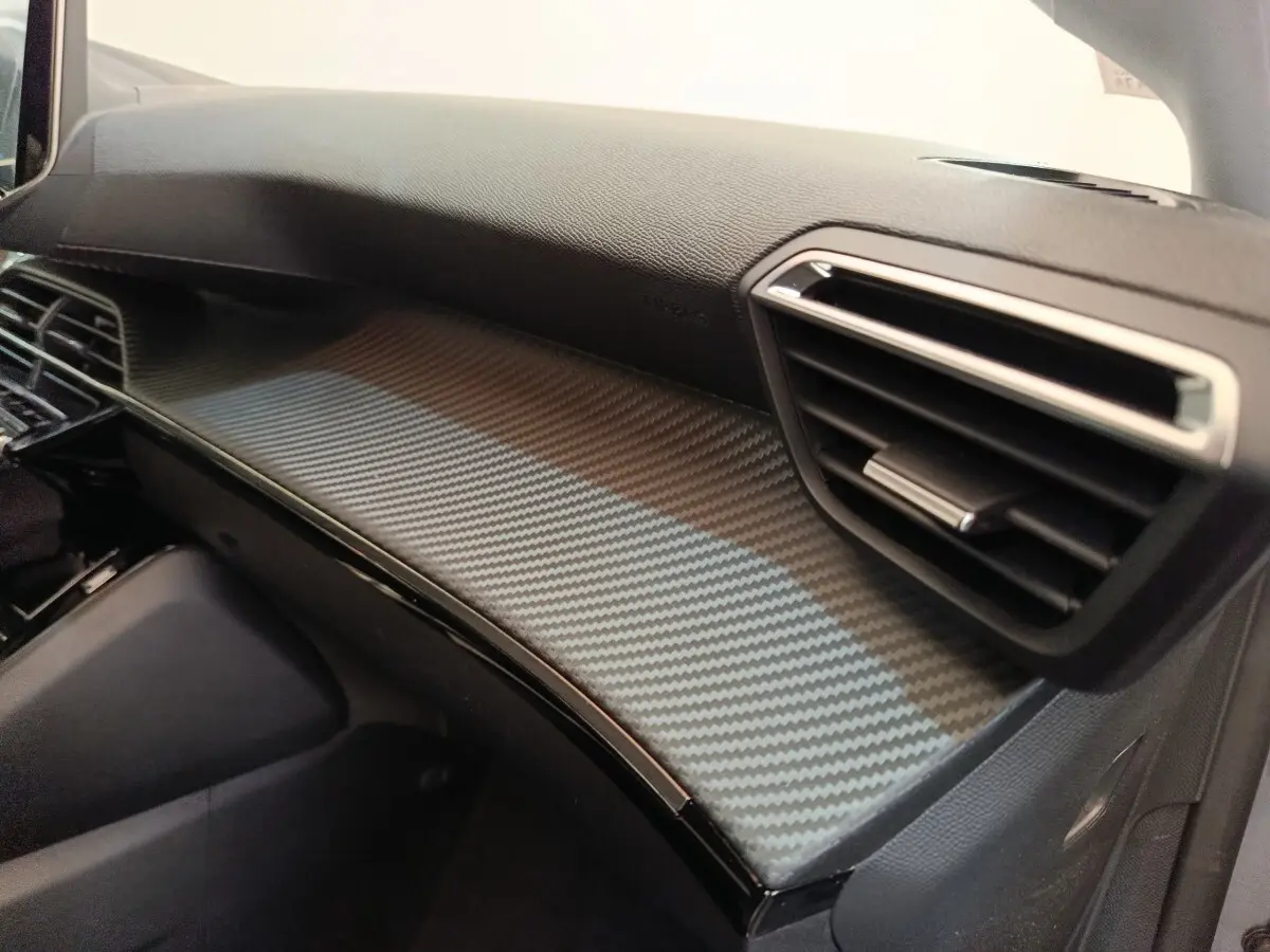 Vue intérieure côté passager du tableau de bord gris foncé avec finition carbone du Peugeot 208 Electrique ROADTRIP 2022.