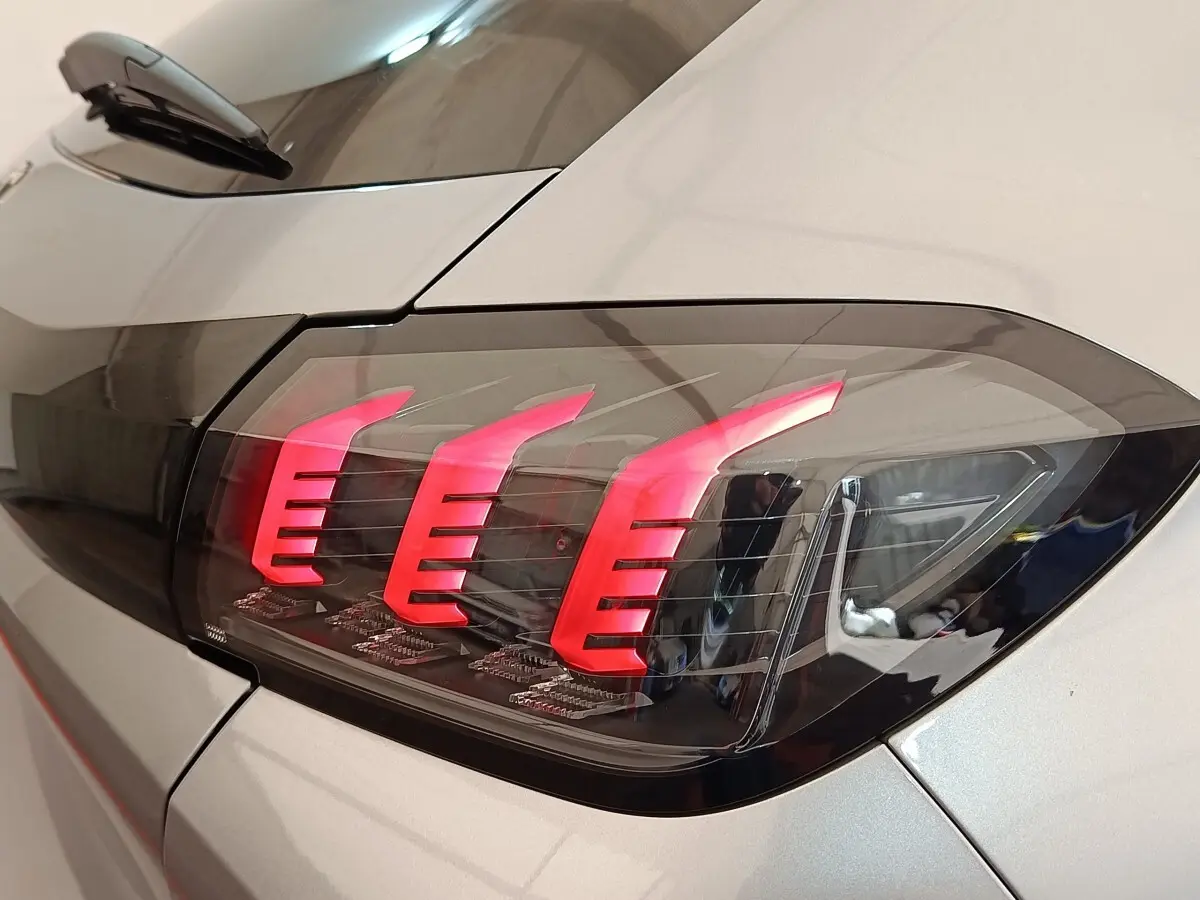 Gros plan sur le feu arrière droit rouge vif d'une Peugeot 208 électrique gris clair, finition Roadtrip 2022.