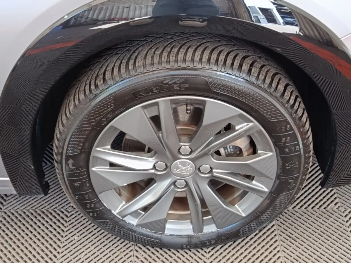 Gros plan sur la roue avant gauche gris clair d'une Peugeot 208 Electrique ROADTRIP 2022 avec jante alliage.