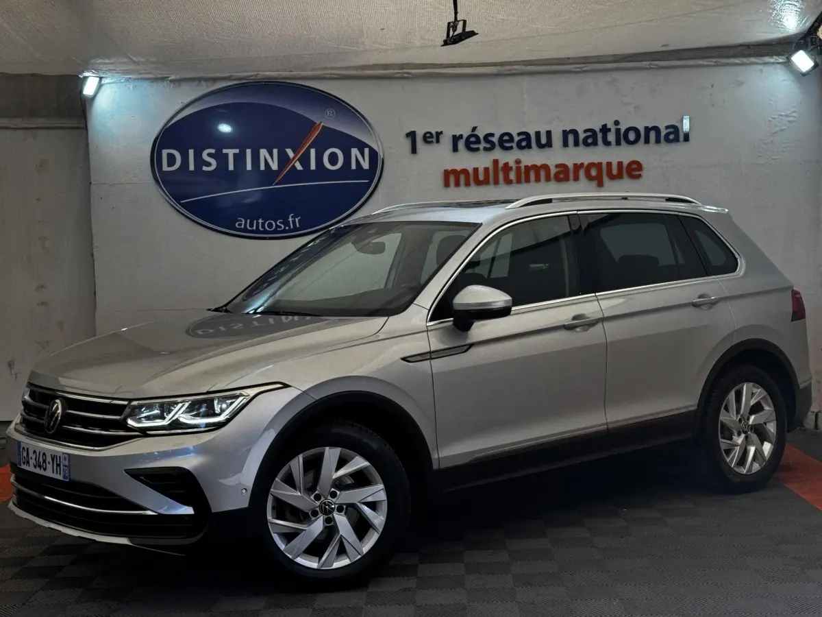 Volkswagen Tiguan gris clair vu de profil droit en intérieur avec jantes alliage et toit ouvrant chromé.