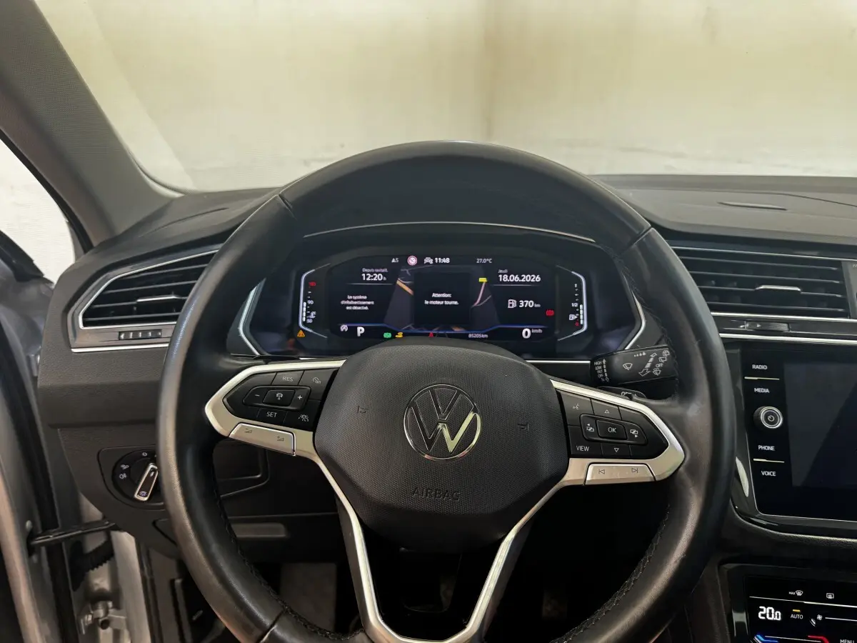 Vue intérieure centrée sur le volant cuir noir et le tableau de bord numérique du Volkswagen Tiguan gris clair 2021.