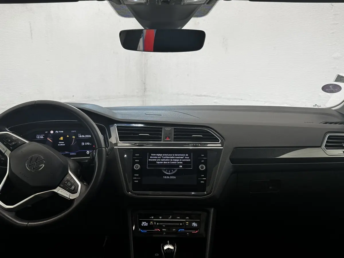 Vue frontale de l’habitacle du Volkswagen Tiguan 2021, tableau de bord noir avec écran tactile central et volant multifonctions.