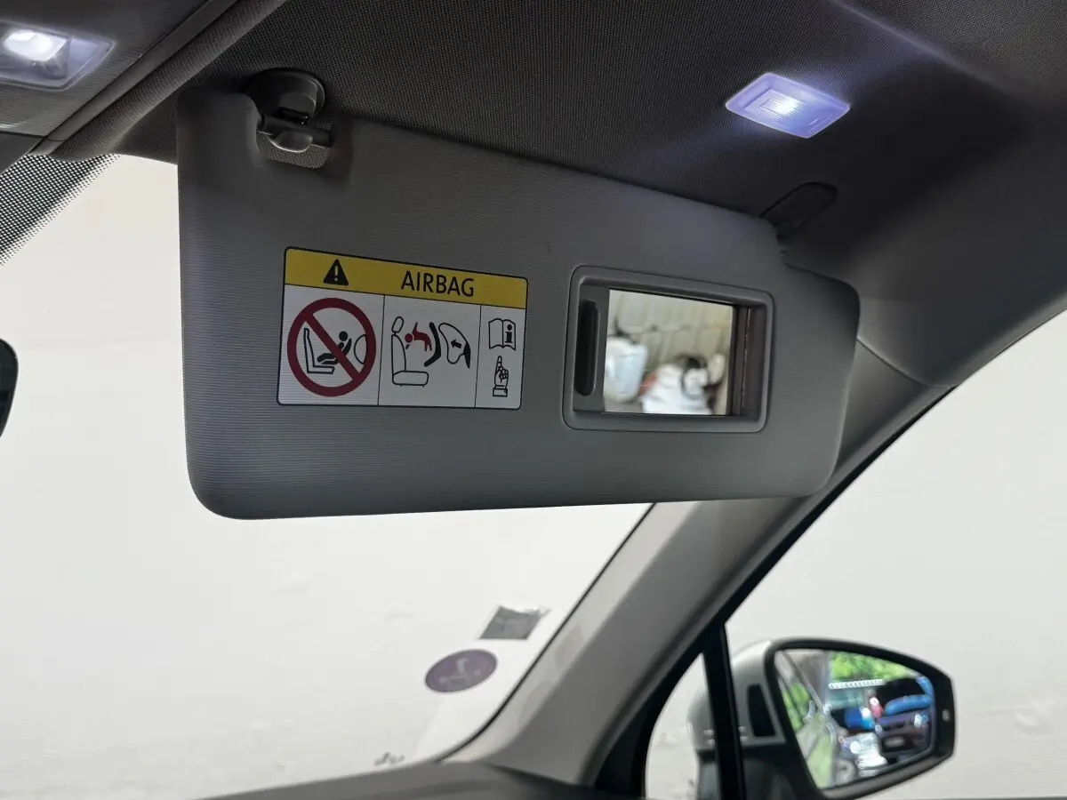 Détail du pare-soleil côté conducteur gris avec miroir intégré et avertissement airbag, intérieur Volkswagen Tiguan 2021.