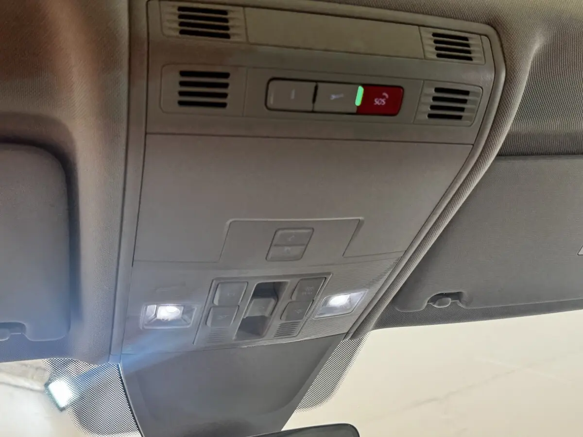 Plafonnier intérieur avec commandes d’éclairage et bouton SOS du Volkswagen Tiguan gris clair, vue en contre-plongée.