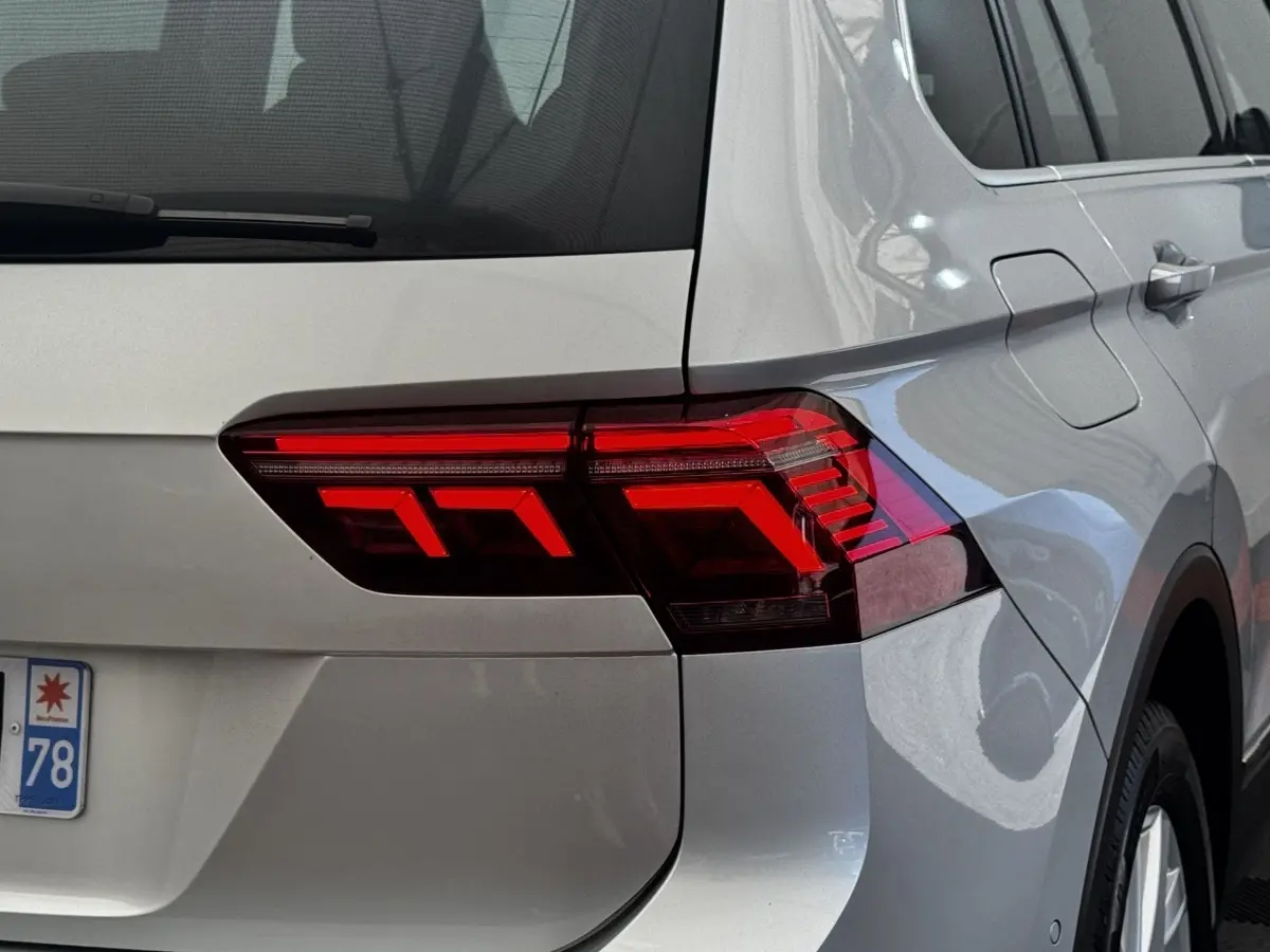 Gros plan sur le feu arrière droit rouge d’un Volkswagen Tiguan gris clair, avec partie latérale et coffre visibles.