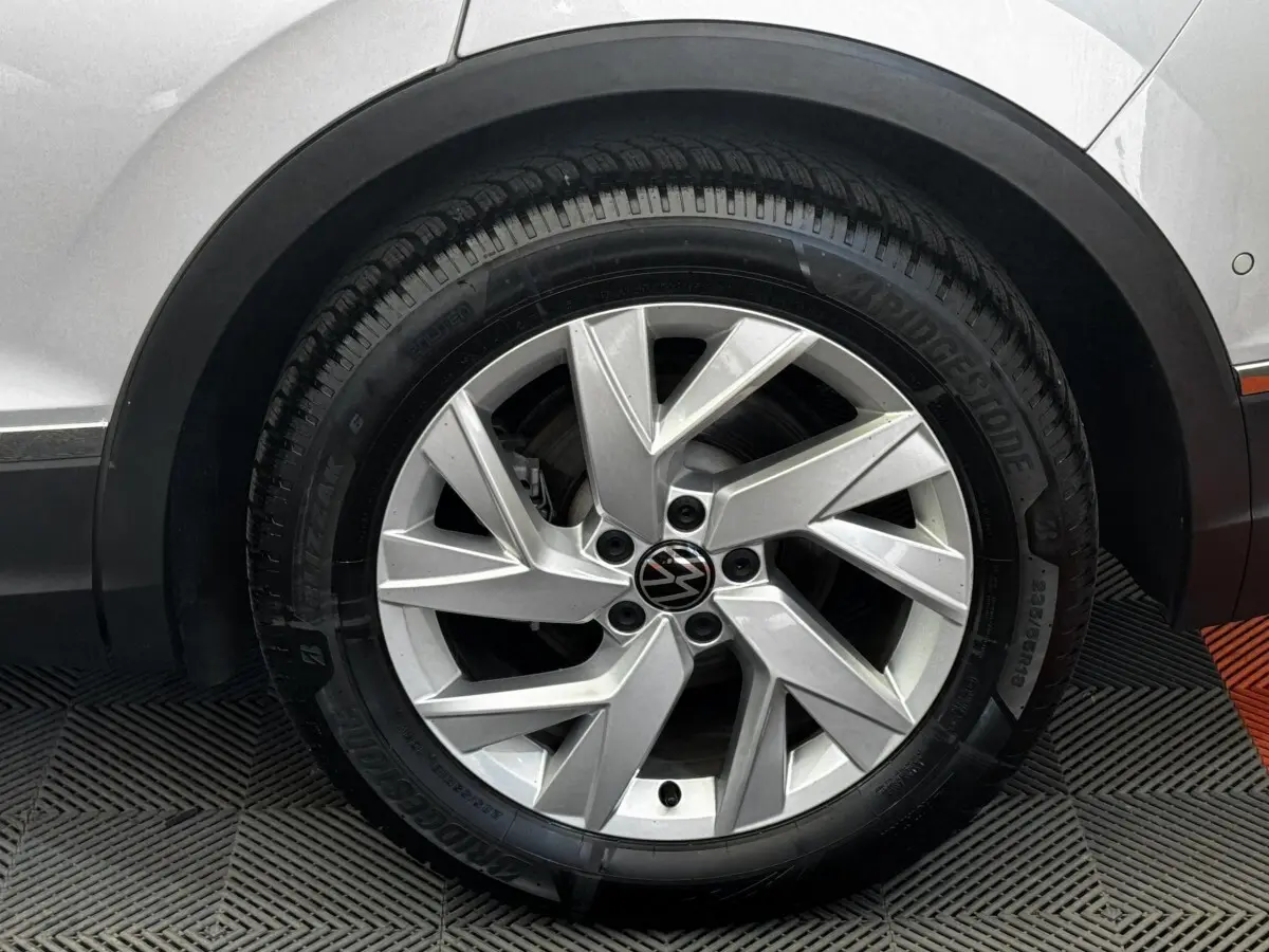 Gros plan sur la roue avant droite gris clair du Volkswagen Tiguan 1.5 TSI 150 DSG7 Elegance avec jante alliage moderne.