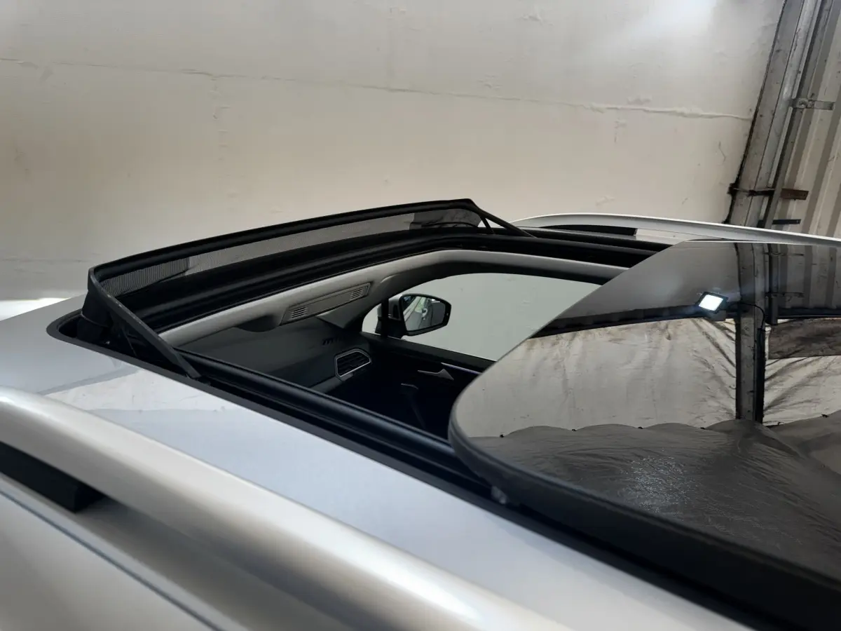 Vue rapprochée du toit ouvrant panoramique ouvert sur un Volkswagen Tiguan gris clair, intérieur partiellement visible.